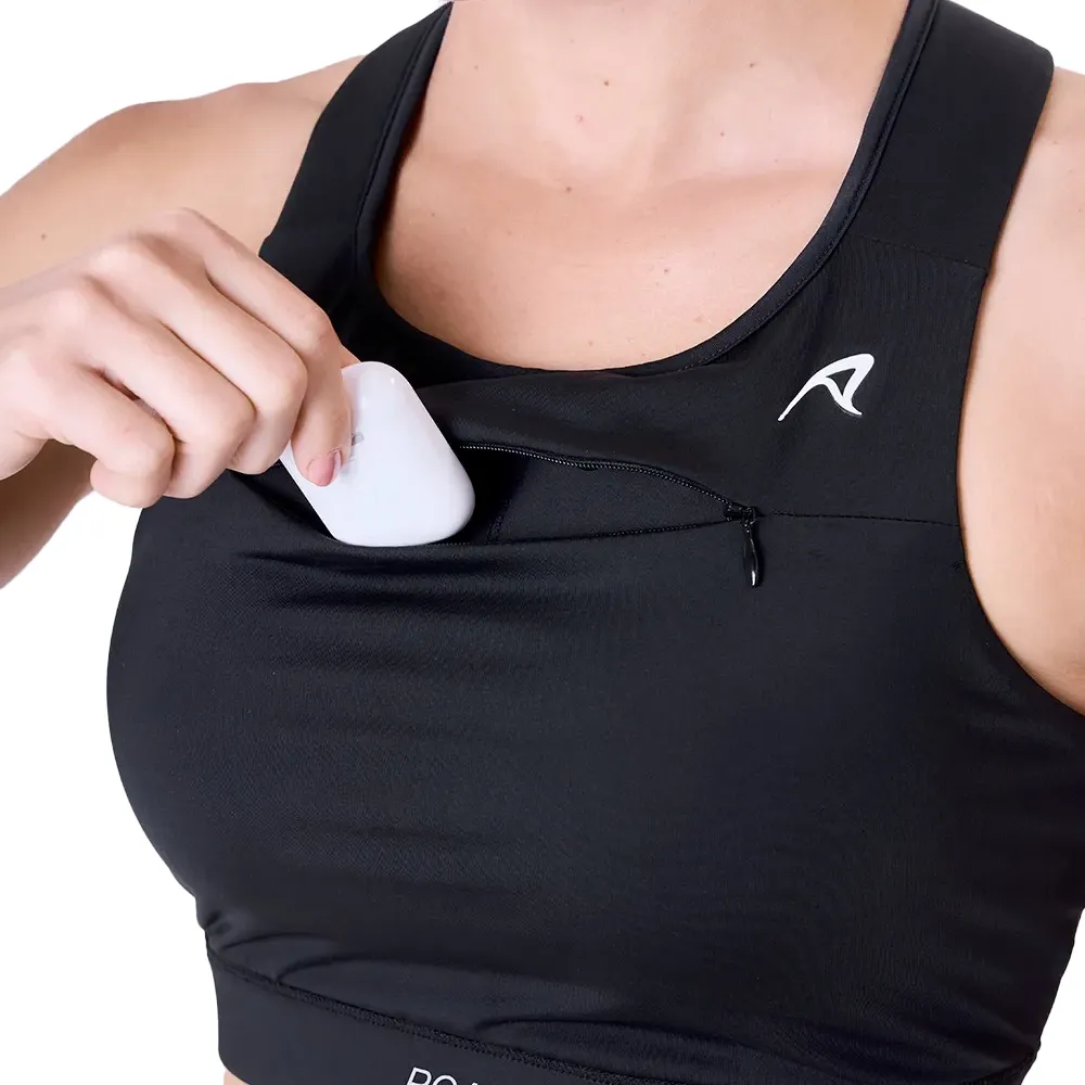 Top esportivo feminino preto com recortes nas costas e bolsos laterais, mostrando smartphone no bolso